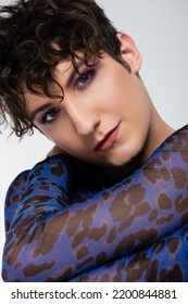 Portrait Of Nonbinary Model With Trendy Hairstyle And Makeup Looking At Camera Isolated On Grey