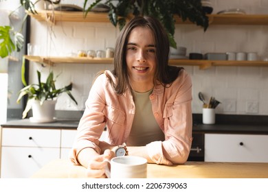 Portrait of non-binary trans woman with coffee cup smiling in the kitchen at home. concept of gender fluidity - Powered by Shutterstock