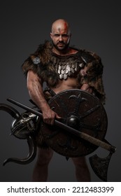 Portrait Of Nordic Warrior With Muscular Build And Horned Helmet Against Gray Background.