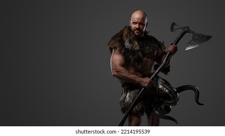 Portrait Of Nordic Warrior With Muscular Build Dressed In Armor Holding Axe.