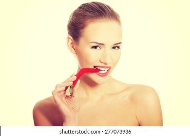 Portrait Of Nude Woman Biting A Chilli Pepper.