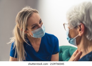 Portrait Of A Nurse In A Blue Uniform Listening To And Taking Care Of Her Elderly Gray-haired Patient. High Quality Photo