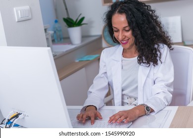 Portrait Of A Nurse ( Female Physician ) Typing A Medical Report On Her Computer In The Lobby.