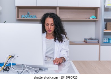 Portrait Of A Nurse ( Female Physician ) Typing A Medical Report On Her Computer In The Lobby.