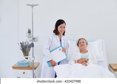 Portrait Of Nurse And Senior Female Patient In Bed