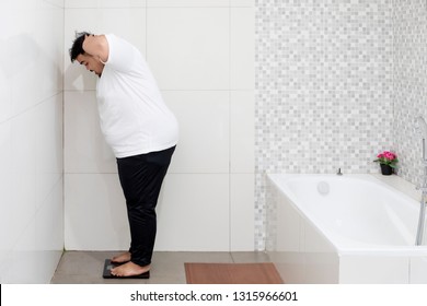 Portrait Of An Obese Man Looks Shocked While Standing On The Scale. Shot In The Bathroom