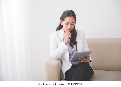 A Portrait Od A Young Asian Female Doctor Reading Something On The Tablet Pc And Smiling To Camera