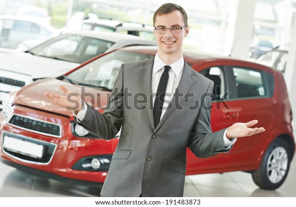 Portrait og salesperson or manager of car\
automobile dealer welcoming with open\
arms