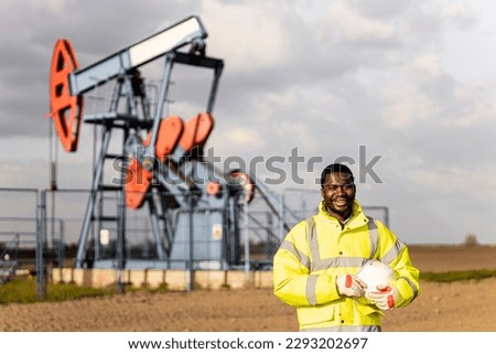 Portrait of an oil field worker standing in front of the oil rig.