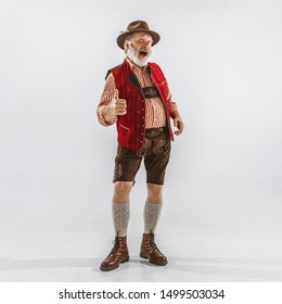 Portrait of Oktoberfest senior man in hat, wearing the traditional Bavarian clothes. Male full-length shot at studio on white background. The celebration, holidays, festival concept. Showing cool.