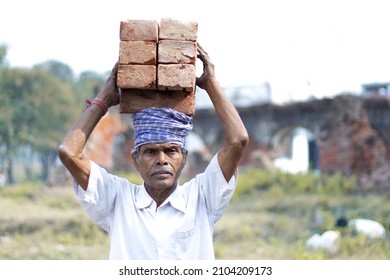 Portrait Of An Old Asian Labour Working At Construction Area. Carrying Bricks On His Head. Labour Day 2022 