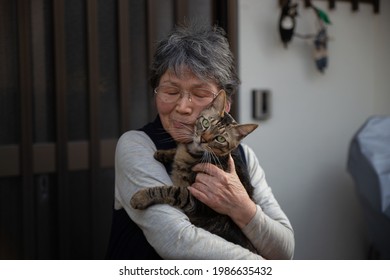 Portrait Of An Old Asian Lady Holding A Brown Patch Cat In Japan.