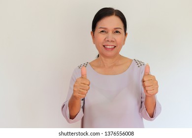 Portrait of old Asian woman show thumbs up and smile with happiness on white background. Healthy concept.