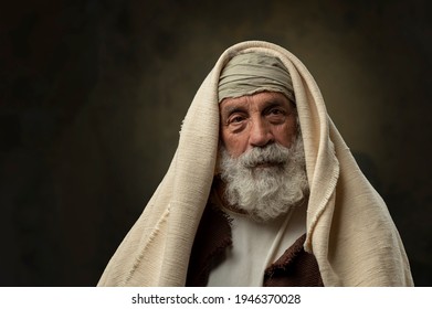 Portrait of old bearded man with ancient attire against a grungy background