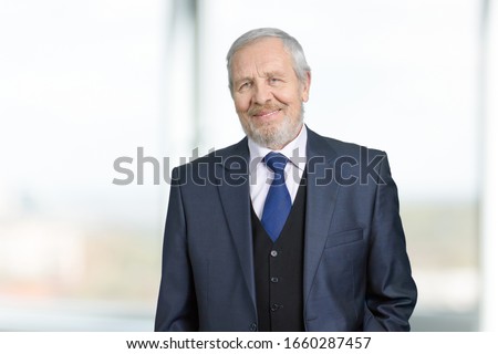 Portrait of old businessman. Senior 70 years old man in business suit. Bright blurred background.