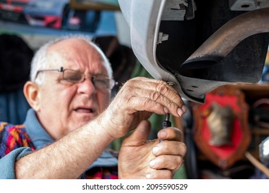 Portrait of an old car mechanic checking and repairing a lifted automobile in his garage. Tinsmith working on a car. Old car mechanics and repair concept. Selective focus. - Powered by Shutterstock