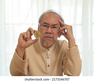 Portrait Of Old Elderly Asian Senior Man Holding Bitcoin Or BTC To Invest On Cryptocurrency. People Lifestyle. Digital Money On Blockchain Technology On Internet. Retirement