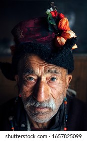 Portrait of an old man in typical tibetan clothes inside his house in Ladakh, Kashmir, India.