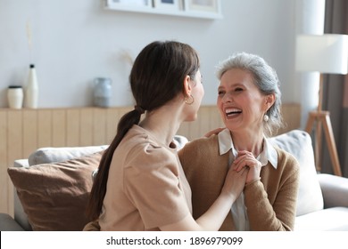 Portrait of old mother and mature daughter hugging at home. Happy senior mom and adult daughter embracing with love on sofa