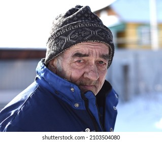 Portrait Of Old Russian Man Looking Sadly In The Camera On Winter Background