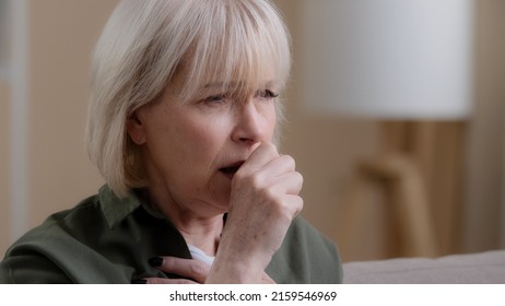 Portrait Old Woman Coughing At Home. Close Up Unwell Caucasian Aging Mature Lady Coughs Having Pain In Chest Coronavirus Symptoms. Grandmother Suffer From Sore Throat Cold Flu Virus Cough Infection