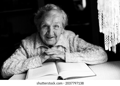 Portrait Of An Old Woman Reading A Book. Black And White Photo. 