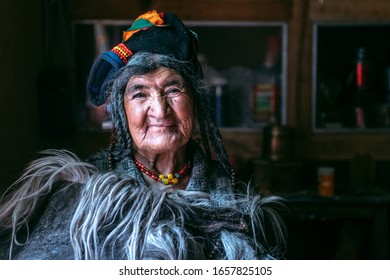 Portrait of a old woman in typical tibetan clothes inside her house in Ladakh, Kashmir, India.