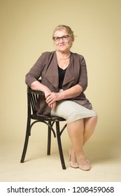 Portrait of an old woman wearing glasses on a beige background