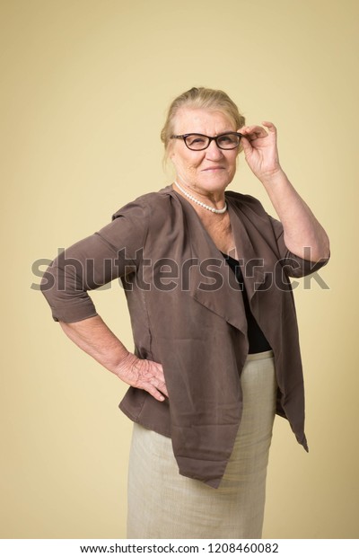 Portrait of an old woman wearing glasses on a\
beige background