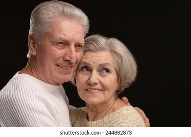 Portrait Of Older Couple Embracing On A Black Background