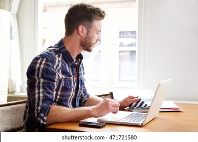 Portrait Of Older Man Working At Desk With Binder And Laptop Thinking