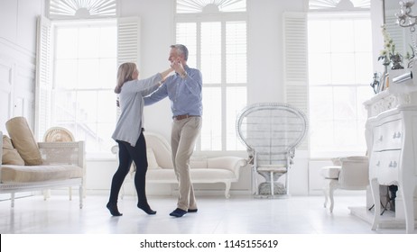 Portrait Of Older Mature Couple In Love Dancing In Their White Apartment