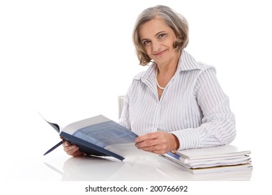 Portrait Of An Older Smiling Businesswoman Sitting At Desk.