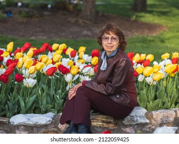 Portrait Of Older Woman With Colorful Tulips In Background; Spring In Midwest, USA