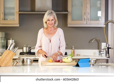 Portrait Of Older Woman In Kitchen Cutting Vegetables