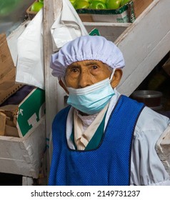 Portrait Of An Older Woman Selling Fruit In A Greengrocer. Food Market. Woman With Face Mask Selling Fresh Produce