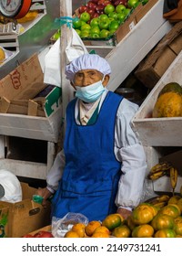 Portrait Of An Older Woman Selling Fruit In A Greengrocer. Food Market. Woman With Face Mask Selling Fresh Produce