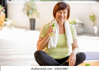 Portrait Of An Older Woman In Sportswear Drinking Water After The Exercising Indoors At Home Or Gym