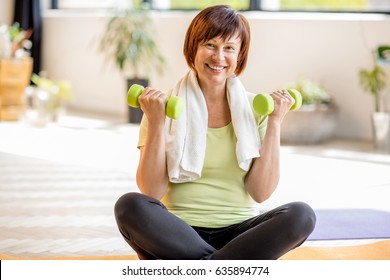 Portrait Of An Older Woman In Sportswear Exercising With Dumbbells Indoors At Home Or Gym