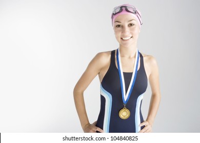 Portrait of an olympic swimmer wearing a gold medal and smiling at the camera.