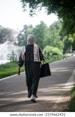 Portrait on back view of Veiled Muslim woman walking in the street 