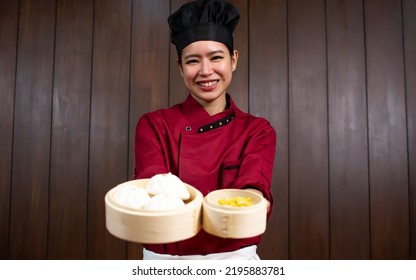 Portrait One Beautiful Traditional Professional Chinese Chef Wearing Red Uniform, Hat, Happily Smiling, Presenting Basket Of Food For Advertisement. Restaurant, Food, Hotel Concept