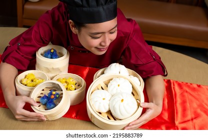 Portrait One Beautiful Traditional Professional Chinese Chef Wearing Red Uniform, Hat, Happily Smiling, Presenting Basket Of Food For Advertisement. Restaurant, Food, Hotel Concept