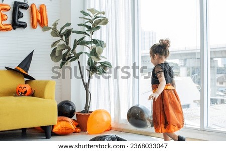 Portrait one little adorable cute Caucasian girl with curly hair wearing witch costume for celebrating Halloween party, staying alone at home with happiness and fun. Kids, Activity, Education Concept