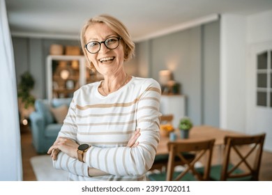 Portrait of one mature blonde caucasian woman with eyeglasses at home happy smile looking to the camera confident wear sweater in bright room copy space