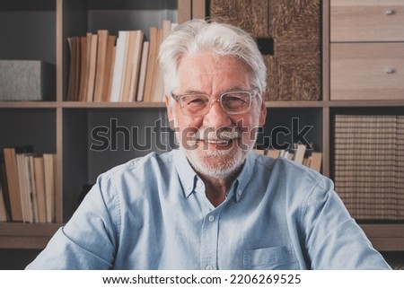 Portrait of one old cheerful male senior smiling having fun at home. Mature caucasian man studying independent looking at the camera and posing to picture.