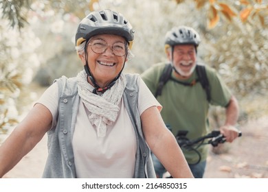 Portrait of one old woman smiling and enjoying nature outdoors riding bike with her husband laughing. Headshot of mature female with glasses feeling healthy. Looking at the camera - Shutterstock ID 2164850315