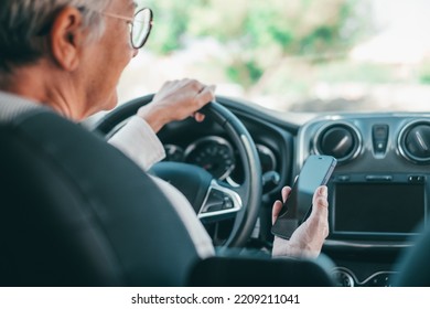 Portrait of one old woman using phone in car while driving in the road risk causing an accident. Close up of hands holding smartphone surfing online texting and chatting. - Powered by Shutterstock