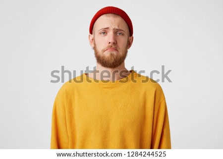 Portrait of one sad bearded man looking upset because of the girlfriend, in a bad mood, ready to cry, with hopeless facial expresion, over white wall