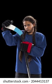 Portrait Of One Young Girl Professional Hockey Player In Blue Uniform, Holding Stick Isolated Over Black Background. Youth Culture. Concepth Of Childhood, Sport, Strength Ad